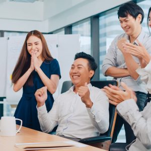 Millennial group of young businesspeople Asia businessman and businesswoman celebrate giving five after dealing feeling happy and signing contract or agreement at meeting room in small modern office.