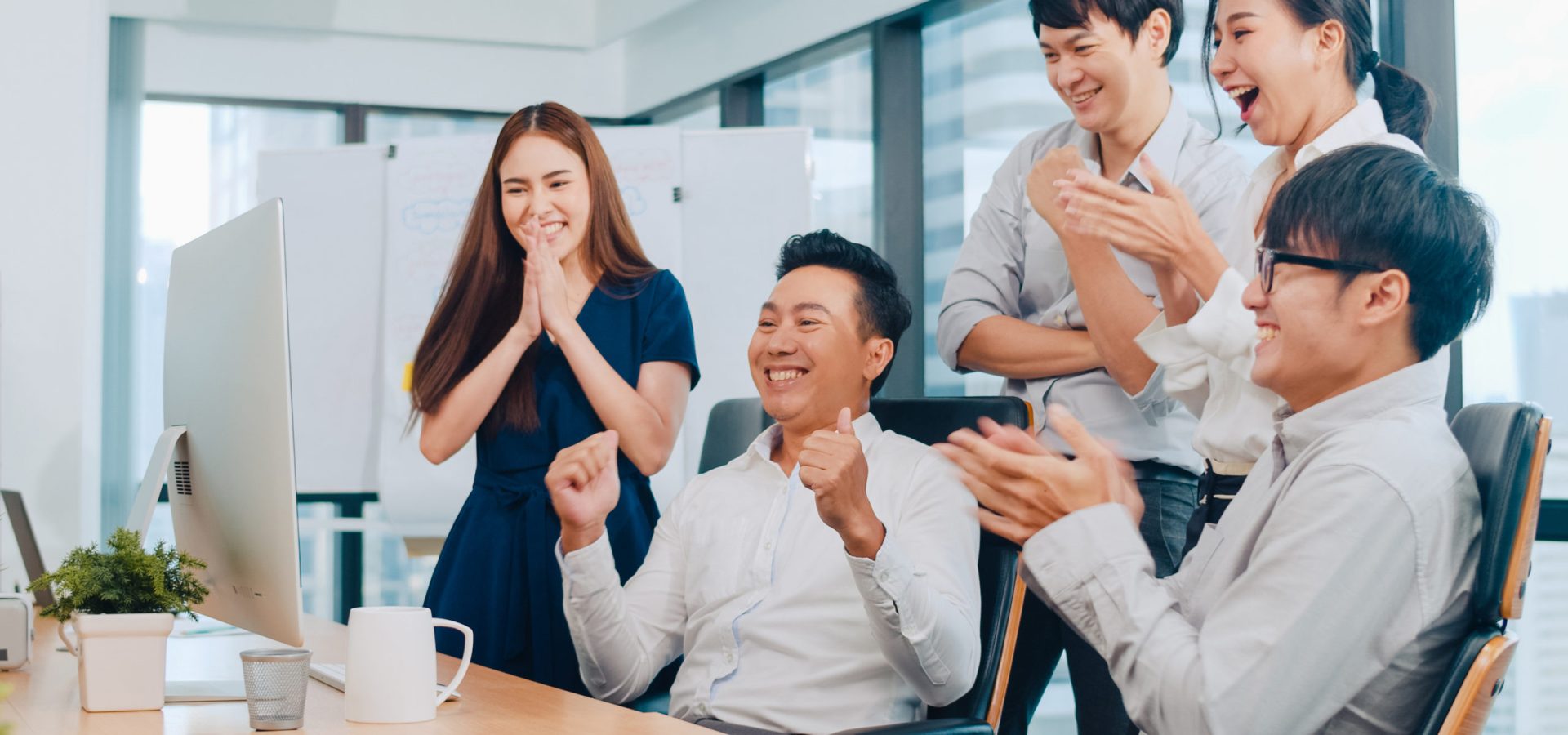 Millennial group of young businesspeople Asia businessman and businesswoman celebrate giving five after dealing feeling happy and signing contract or agreement at meeting room in small modern office.